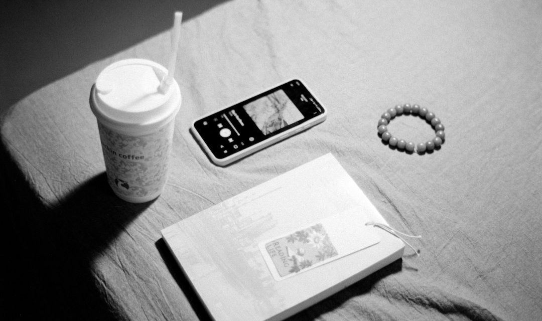 Ponsel dan buku di samping secangkir kopi saat jeda dari layar